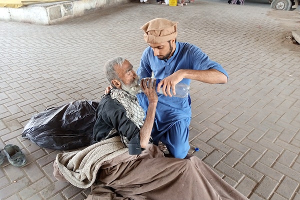 un jeune homme aidant un vieil homme à boire de l'homme